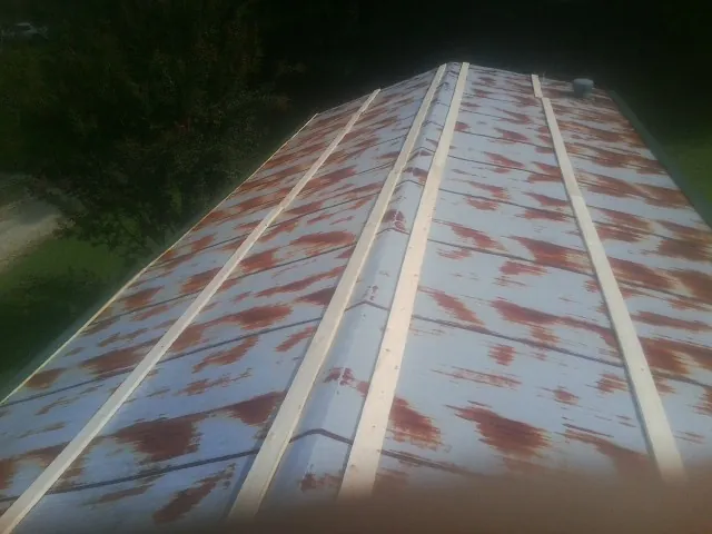 Rusted metal roof panels with new wood purlins before replacement — Storm Damage Roof Repair in Brookpark by Roofing Brothers