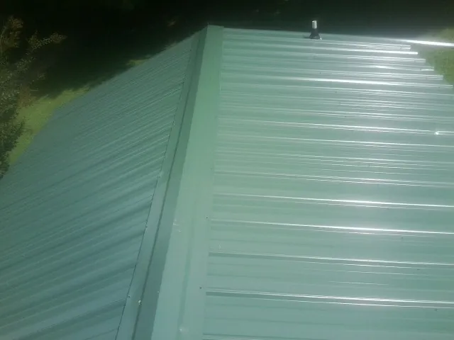 New green metal panels meeting at the ridge of a roof — Flat Roof Repair work by our crew in Brookpark