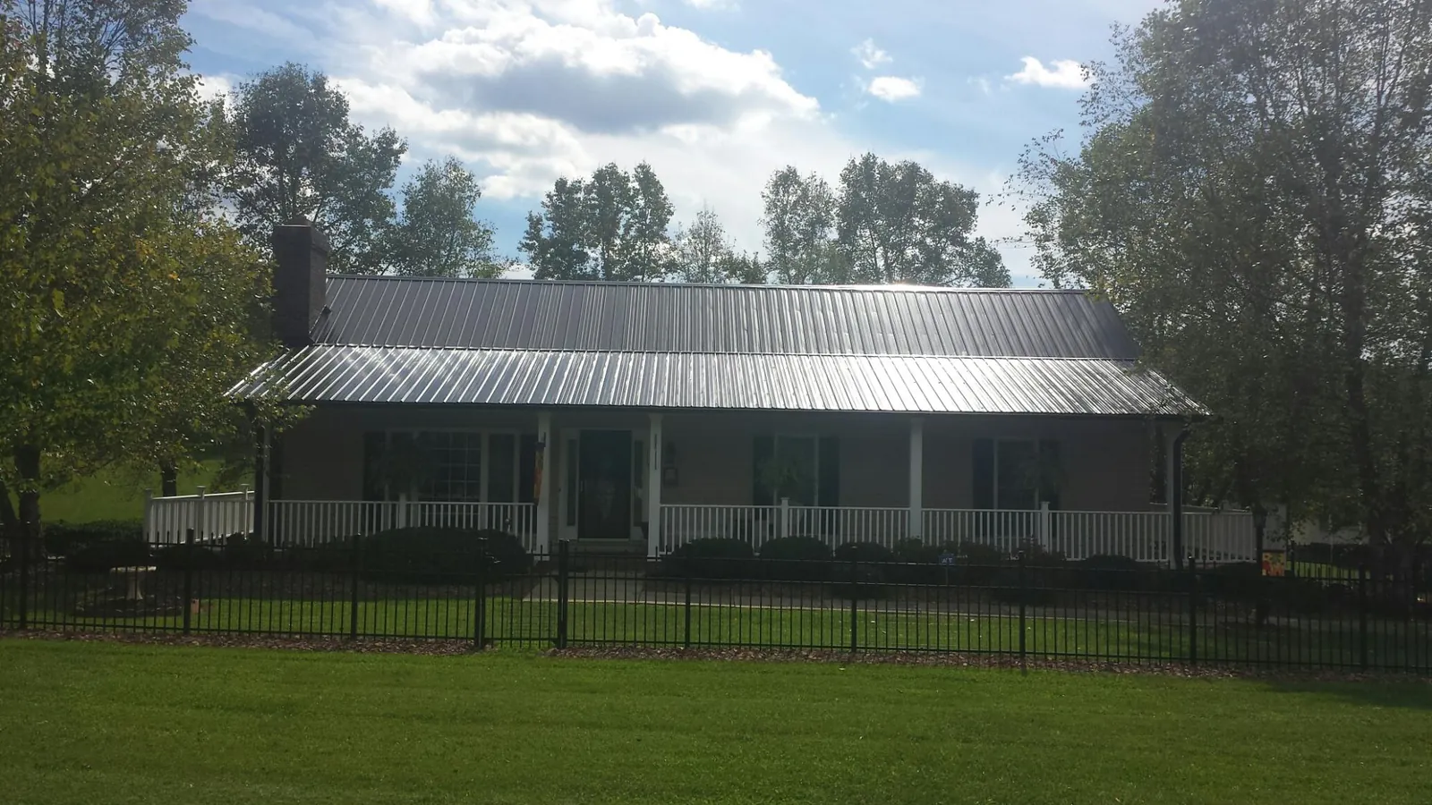 Gray metal roof on a brick ranch with a full width front porch — Gutter Guard Installation work by our crew in Brookpark