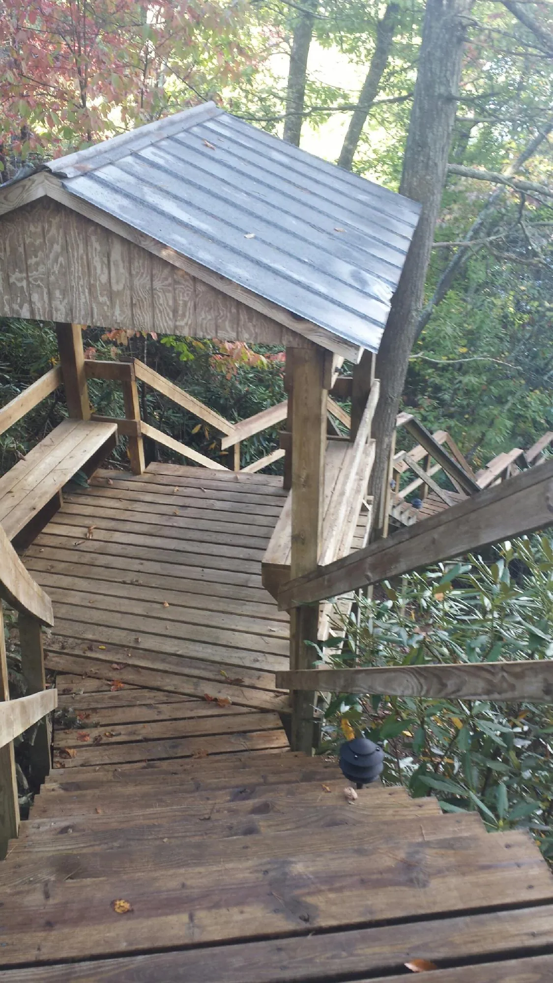 Metal roofed shelter over wooden steps on a wooded walkway — Skylight Repair & Installation work by our crew in Brookpark