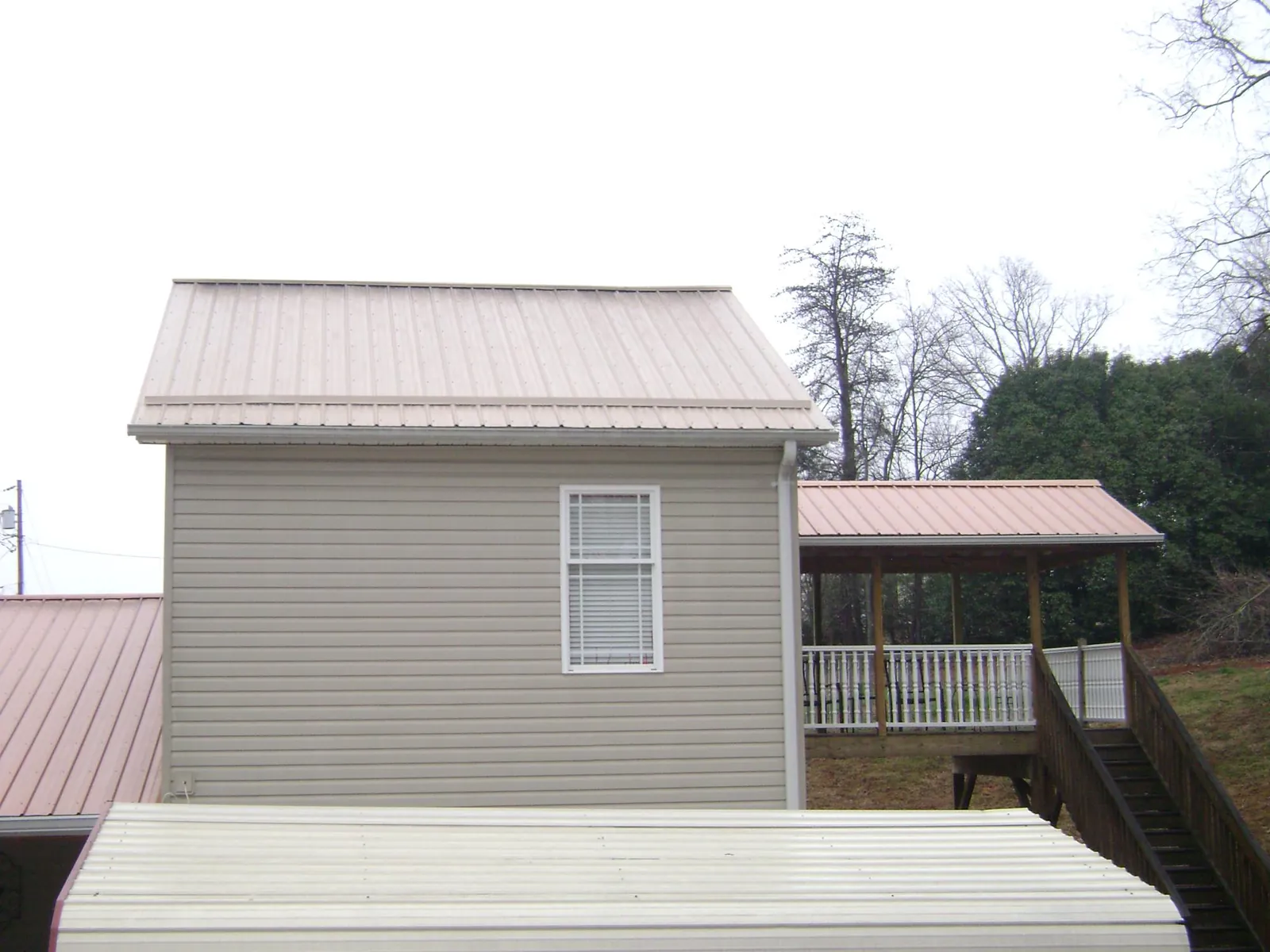Tan metal roofs on a two story addition and attached porch, from a Roof Replacement job in Brookpark